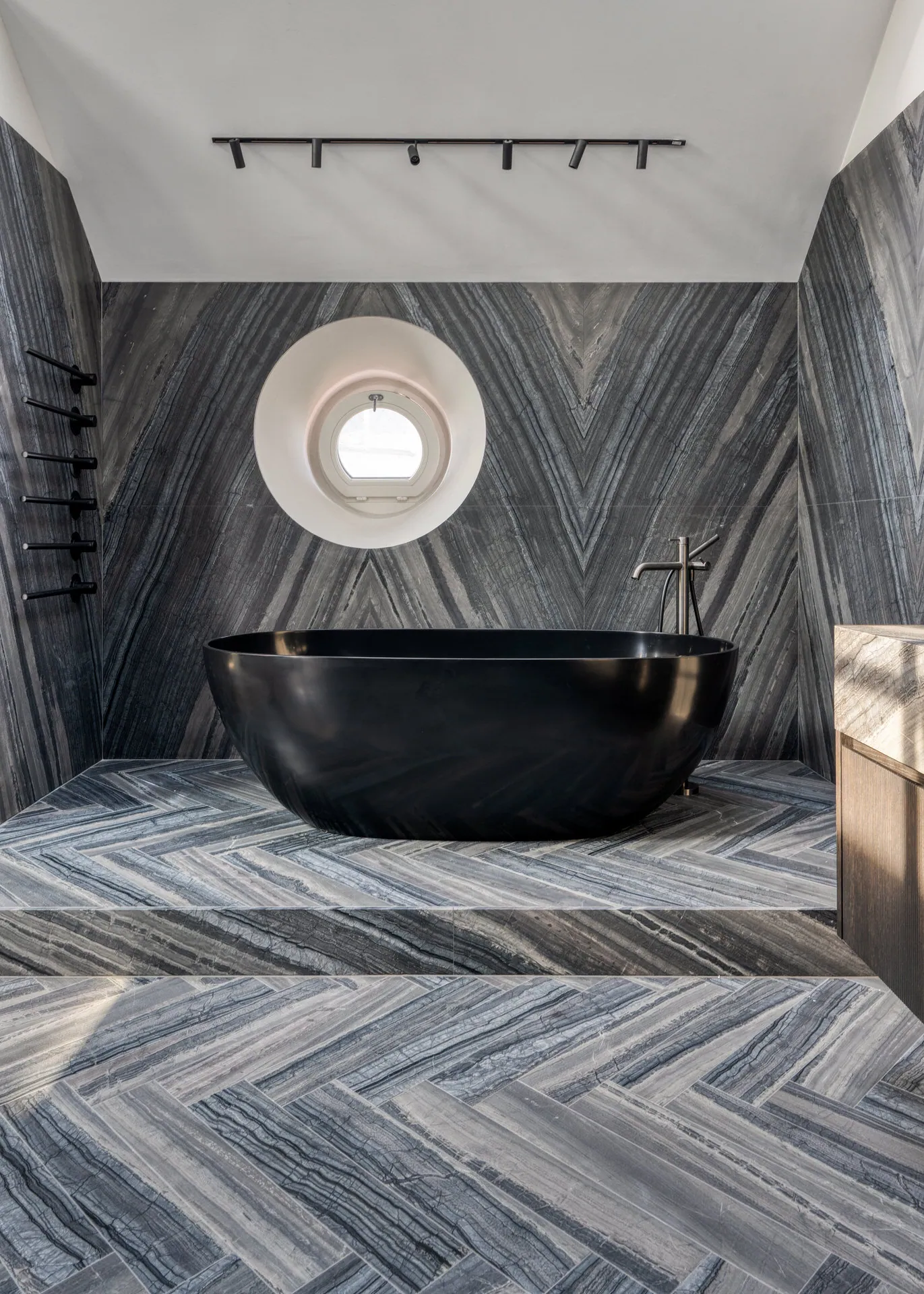 Freestanding black bathtub against marble wall in Vienna penthouse bathroom