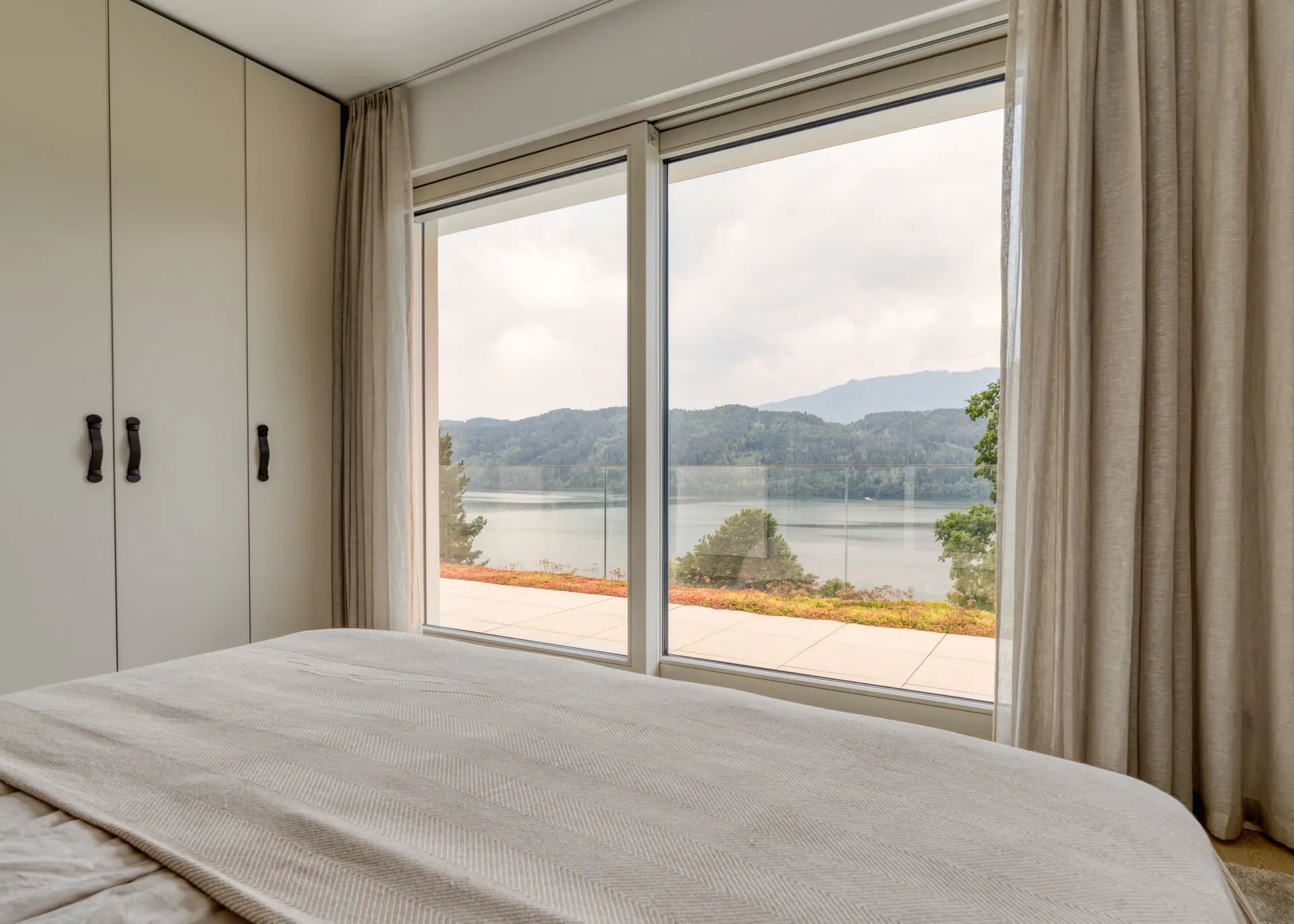 Bedroom with lake view window at Millstätter See luxury apartment