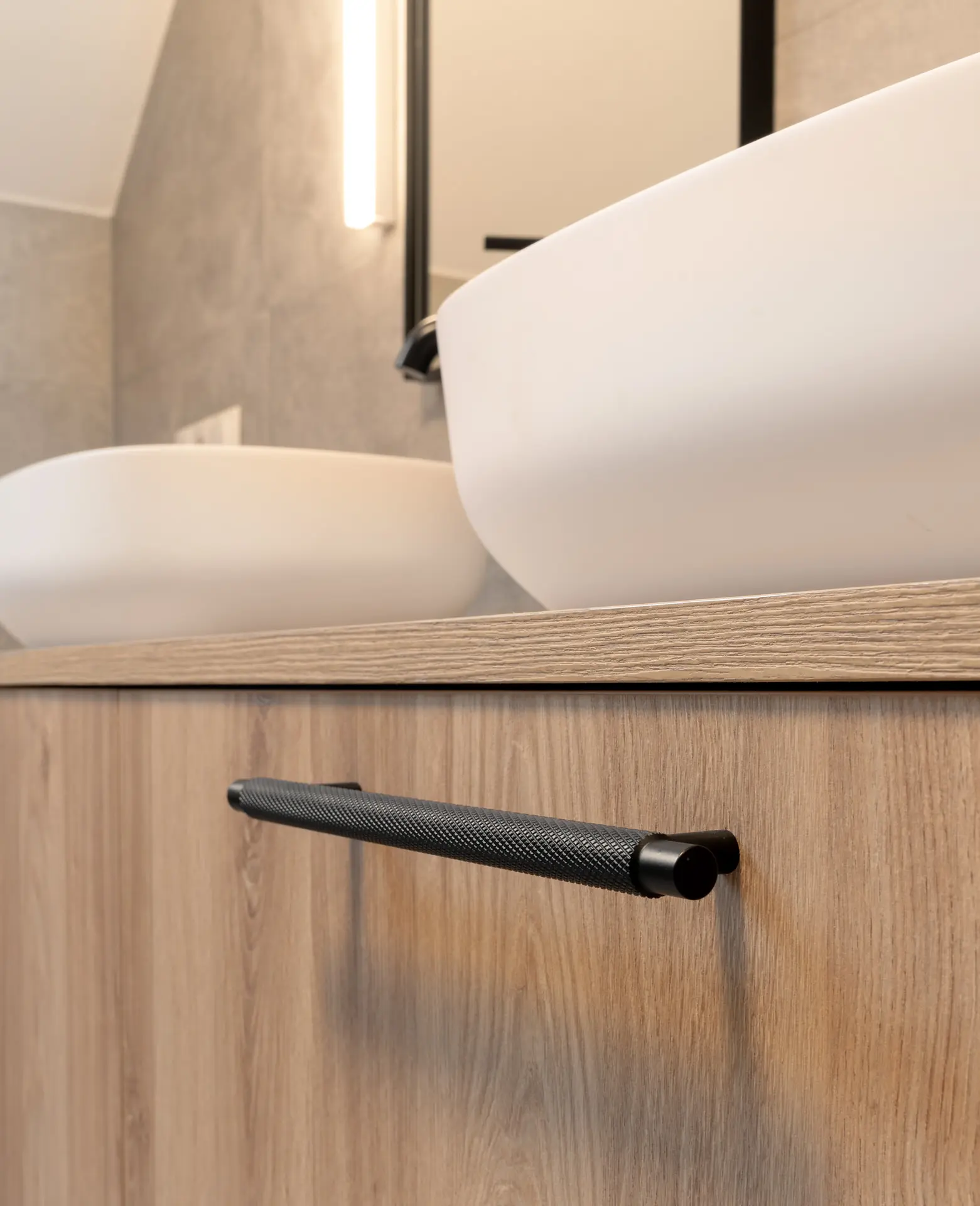 Black knurled handle detail in stone-tiled bathroom of Linz apartment