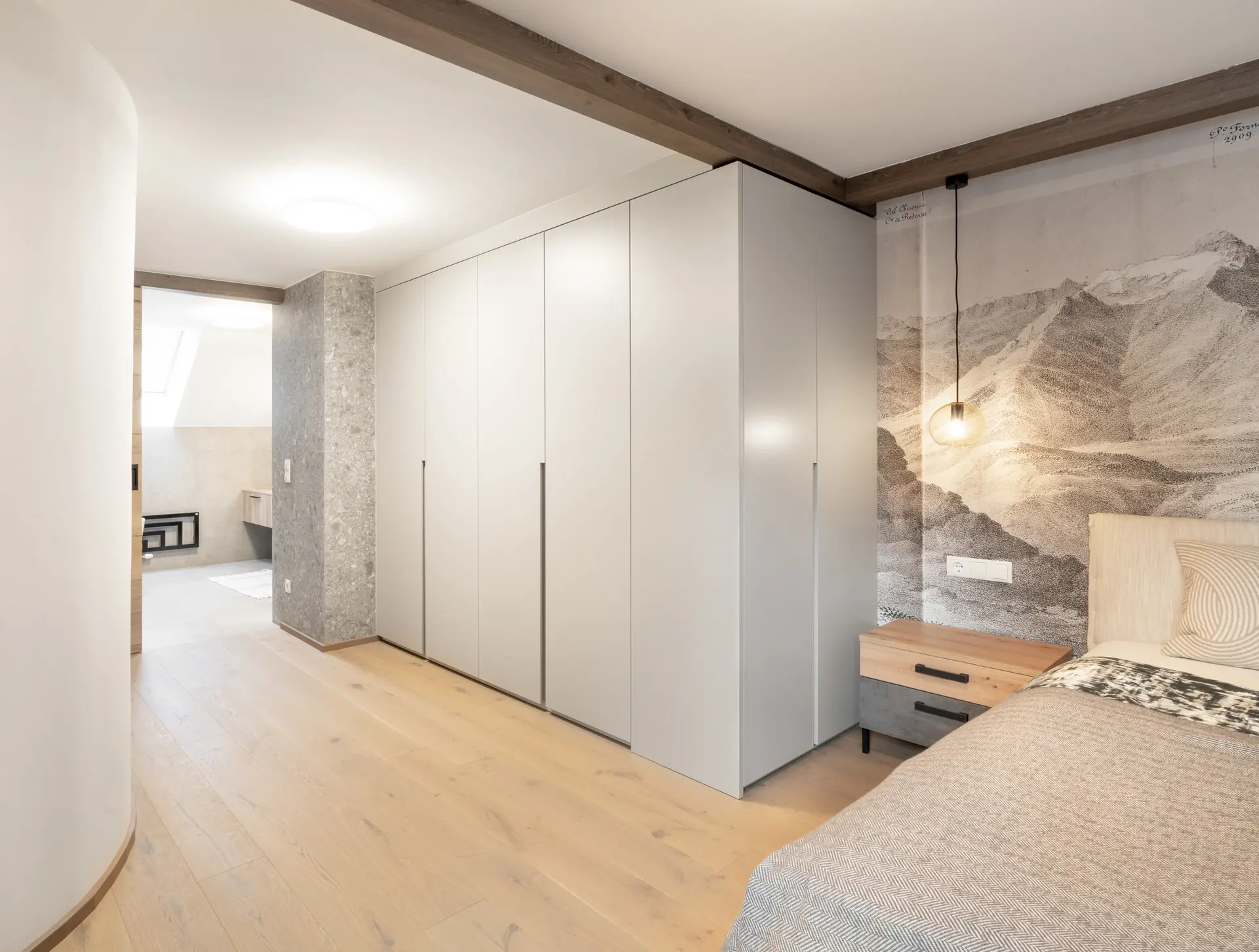 Bedroom with bespoke fitted wardrobes and mountain mural in Linz apartment