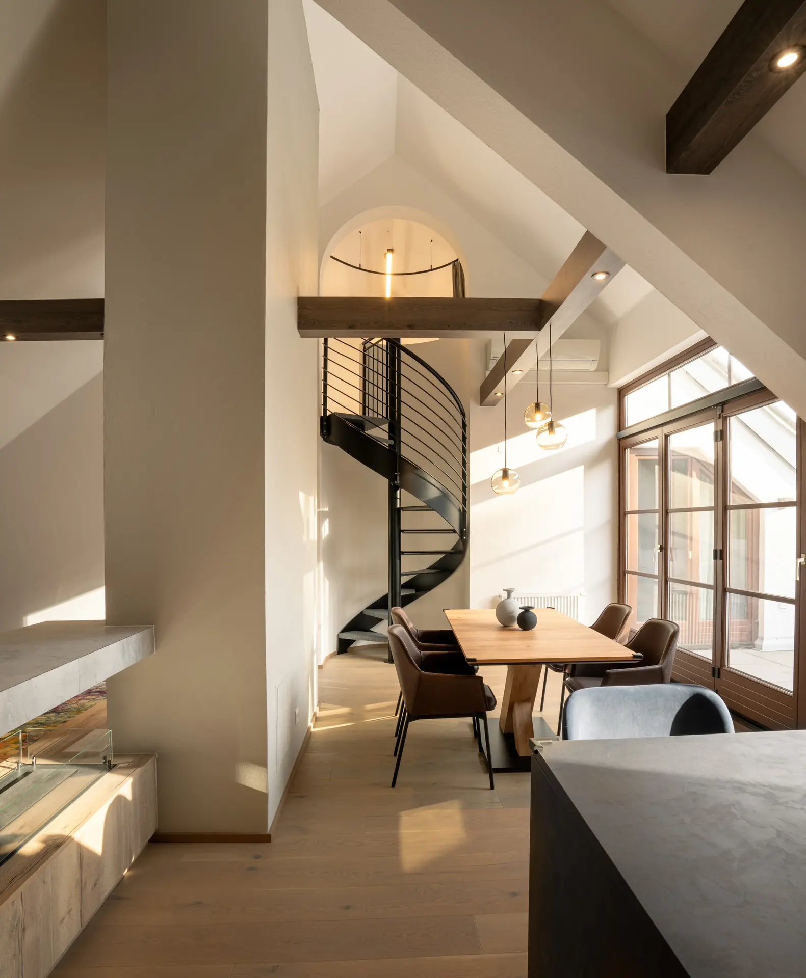 Dining area with sculptural spiral staircase in Linz apartment