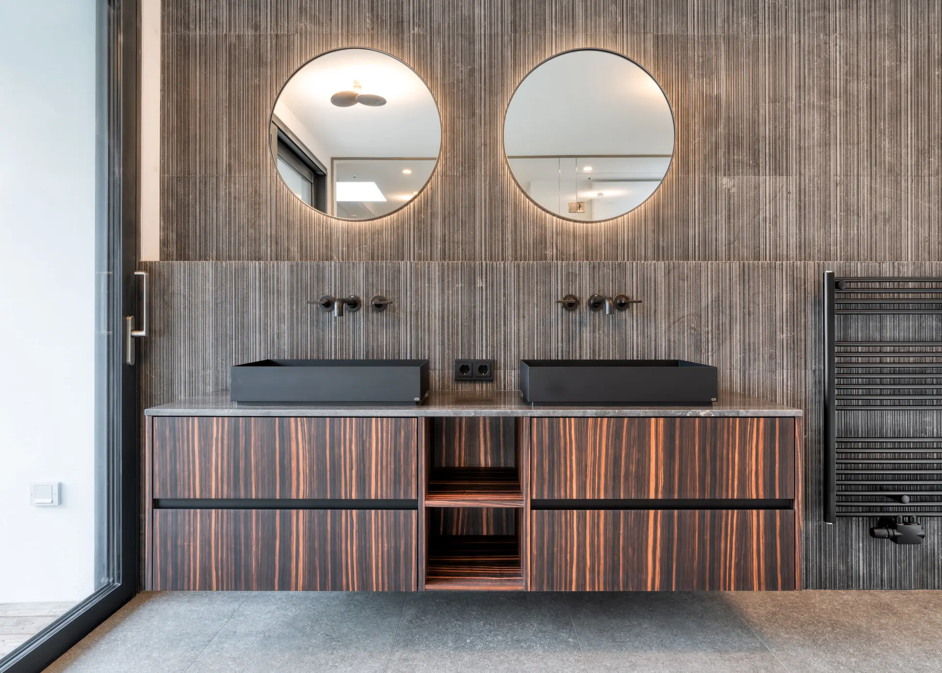 Ensuite bathroom with dual round mirrors in Kitzbuehel private villa